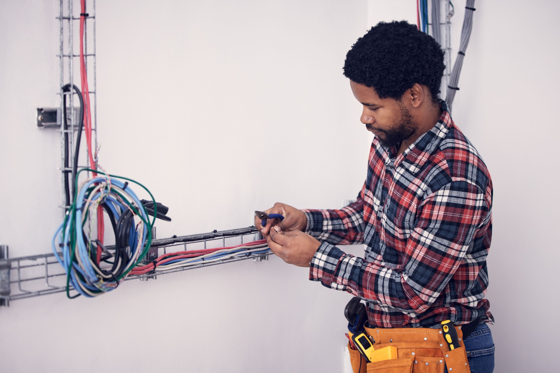 Technician, black man and electrician checking cables, fixing faulty wires and server mechanic. Male employee, entrepreneur and engineer with tools, electrical and maintenance with handyman and focus